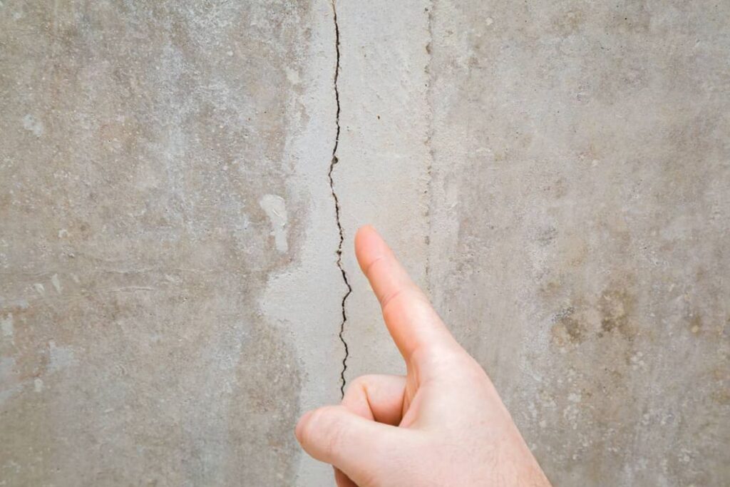 stucco contractor pointing at stucco wall crack